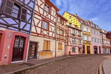 Historic colorful timber houses lining a quiet curved street in Colmar.