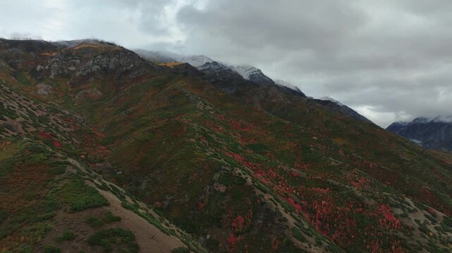 Aerial view of mountain slopes painted with autumn colors meeting rocky peaks touched by early snow, Payson, Utah, United States.