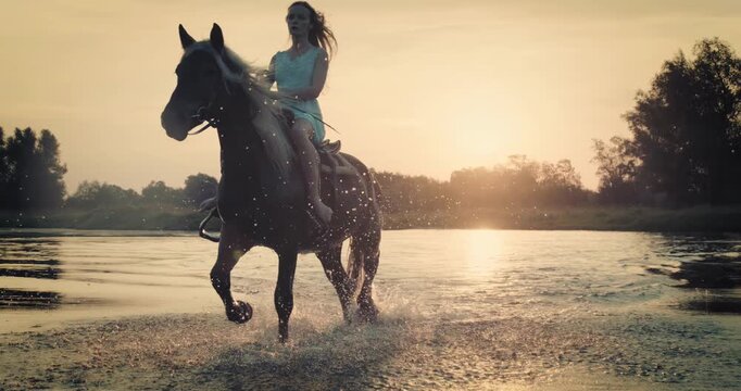 Super slow-motion footage of a rider galloping on horseback through shallow river at sunset. Dramatic splashes and warm golden light create a cinematic outdoor adventure scene.