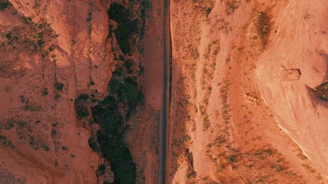Aerial view of the road cutting through the stunning red rock canyons, where shadows accentuate the textures of the landscape, Moab, Utah, United States.