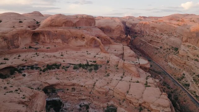 Aerial view of the red rock formations, with a river snaking through the rugged terrain in the desert, Moab, Utah, United States.