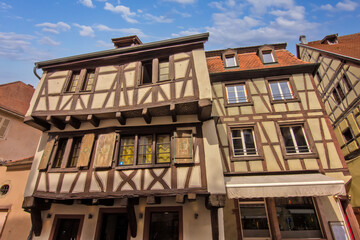 Colorful historic timber houses with flowers lining a narrow street in Colmar.