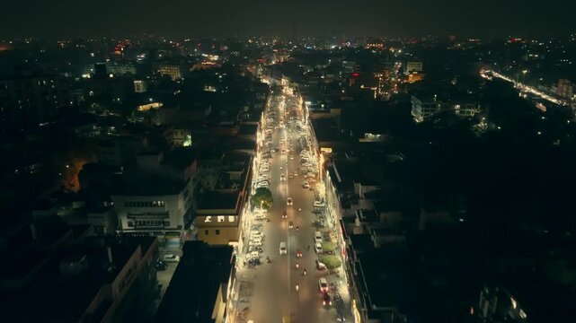 Aerial view of illuminated streets at night, with streams of cars and buildings creating a vibrant contrast against the dark sky, Ashok Nagar, Rajasthan, India.