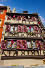 Colorful historic timber houses with flowers lining a narrow street in Colmar.