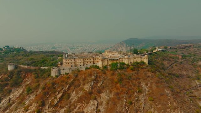 Aerial view of Nahargarh Fort perched atop the rugged Aravalli Range, a beautiful contrast against the distant city skyline, Jaipur, Rajasthan, India.