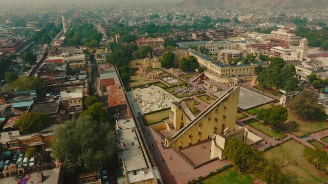 Aerial view of the architectural marvels of Jantar Mantar and Hawa Mahal Road with the city buildings and green trees, Jaipur, Rajasthan, India.