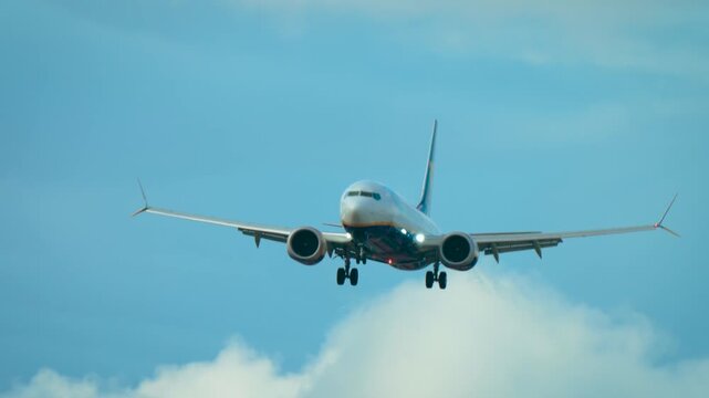 Airliner experiencing strong crosswind with noticeable tilt. Jet adjusting to gusts while flying in partly cloudy sky. Passenger aircraft descending with landing gear down in turbulence. Twin engine