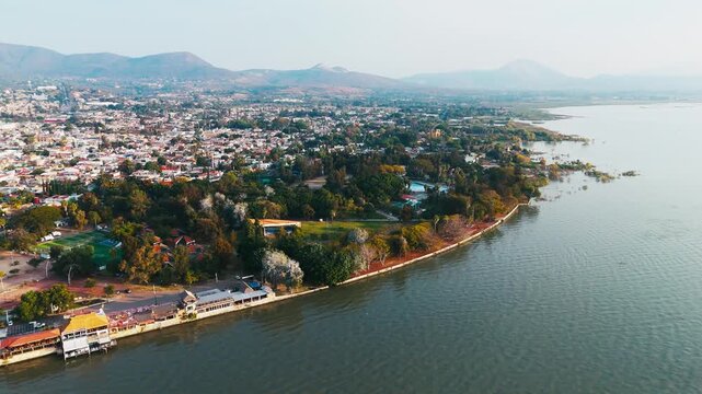 Aerial view of the buildings, lush green trees, and waters of Lake Chapala, contrasting with the urban sprawl, Chapala, Jalisco, Mexico.