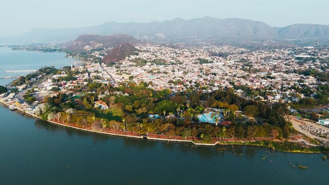 Aerial view of Chapala's vibrant cityscape meeting the serene lake, showcasing a contrast of urban life and natural beauty, Chapala, Jalisco, Mexico.
