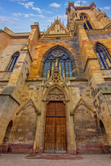 Ornate carved Gothic church doorway in Colmar showing medieval stone sculptures and architecture.