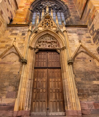 Ornate carved Gothic church doorway in Colmar showing medieval stone sculptures and architecture.