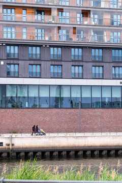 Modern architecture waterfront promenade beside residential apartment building in HafenCity district in Hamburg Germany showing urban life and development