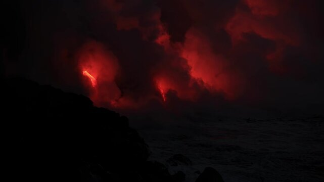 Dramatic volcanic lava flow entering the ocean on the Big Island of Hawaii. Glowing molten lava meets seawater, creating intense steam clouds and fiery red light against a dark coastal landscape.