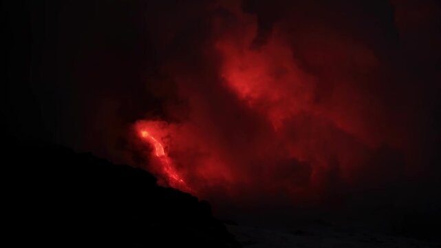 Dramatic volcanic lava flow entering the ocean on the Big Island of Hawaii. Glowing molten lava meets seawater, creating intense steam clouds and fiery red light against a dark coastal landscape.