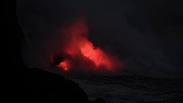 Dramatic volcanic lava flow entering the ocean on the Big Island of Hawaii. Glowing molten lava meets seawater, creating intense steam clouds and fiery red light against a dark coastal landscape.