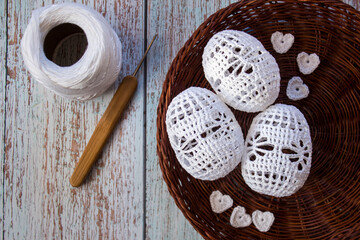 Three white hand-crocheted eggs lie in a rustic woven basket, perfect for Easter, spring decorations, handmade crafts, and cozy home d&eacute;cor with soft artisanal textures.