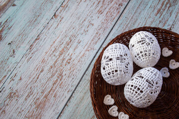 Three white hand-crocheted eggs lie in a rustic woven basket, perfect for Easter, spring decorations, handmade crafts, and cozy home d&eacute;cor with soft artisanal textures.