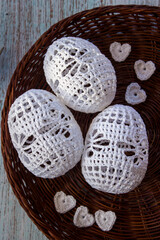 Three white hand-crocheted eggs lie in a rustic woven basket, perfect for Easter, spring decorations, handmade crafts, and cozy home d&eacute;cor with soft artisanal textures.