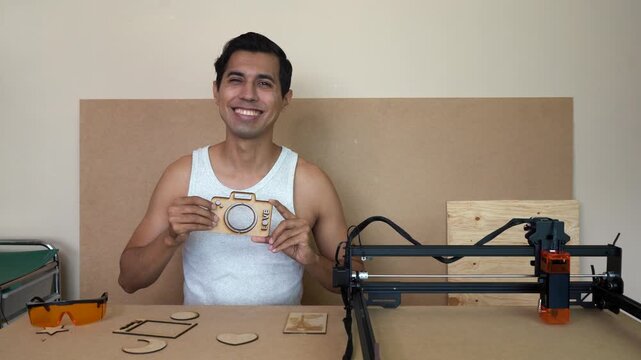 Man cutting MDF with diode laser, smiling creativity indoors
