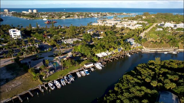 Aerial view of boats docked along the Jupiter Inlet, where the dark water meets lush greenery and buildings, Jupiter, Florida, United States.