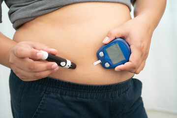 Asian woman injecting herself diabetes injecting insulin in stomach at home.