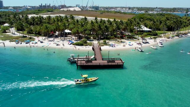 Aerial view of Peanut Island revealing a stretch of sandy beach meeting the turquoise ocean with a boat sailing, West Palm Beach, Florida, United States.