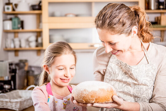 Mother and daughter baking bread in kitchen together