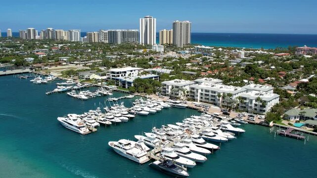 Aerial view of multiple boats docked in a marina, contrasting with the urban skyline and turquoise waters, West Palm Beach, Florida, United States.