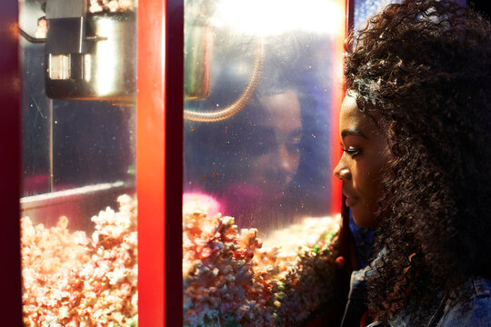 Young woman looking at popcorn in glass case at fair