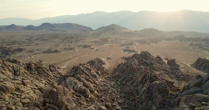 Aerial view of Alabama Hills showcasing the rugged, sun-kissed rocks against the backdrop of distant mountains, creating a stark yet beautiful landscape, Lone Pine, California, United States.