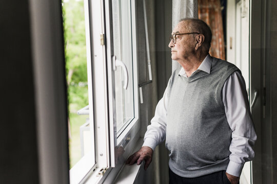 Pensive senior man looking out of window