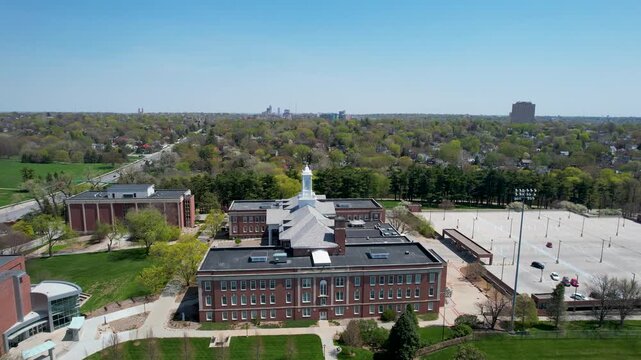 Aerial view of buildings, parking area, and green spaces, a blend of brick structures and lush trees under a clear sky, Omaha, Nebraska, United States.