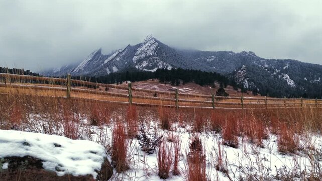 Winter Chautauqua Park Flat Irons Mountain snowing snow flakes falling aerial drone Colorado USA dusk sunrise sunset clouds grass snow covered Rock formation walking loop ground Bear Peak slide right