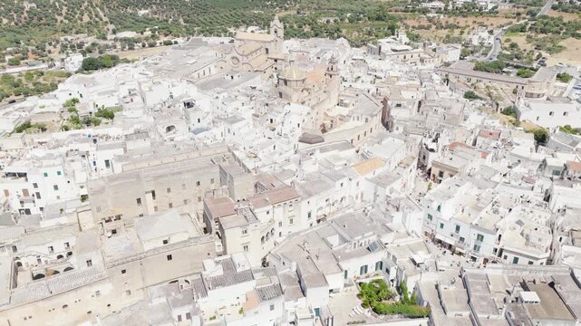 Aerial view of Ostuni's buildings, a cascade of white structures contrasting with the green landscape, Ostuni, Apulia, Italy.
