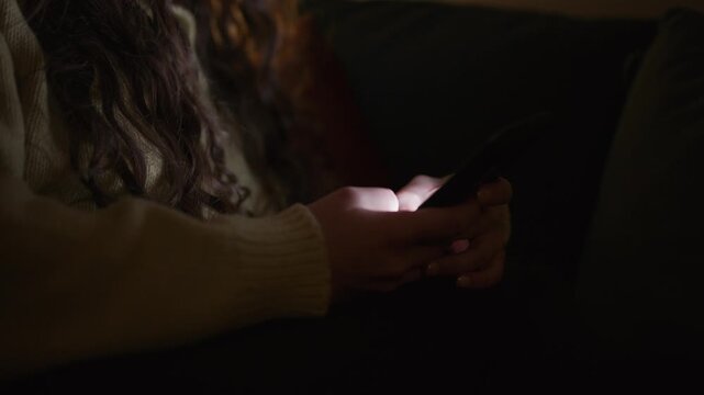 close up of a person scrolling on a smartphone in a dark room, with screen glow illuminating hands and face, representing late night screen time digital habits and modern technology lifestyle concepts