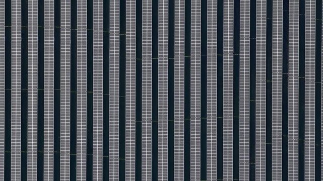 Aerial view of vast solar panels creating a striking visual pattern of alternating dark and light stripes, Wittelsheim, Grand Est, France.