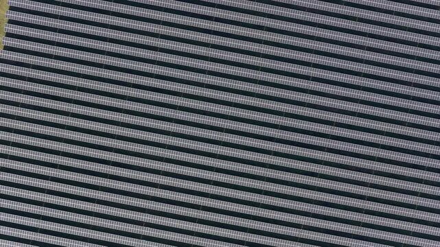 Aerial view of a vast array of solar panels in parallel rows, creating a striking pattern of light and dark lines, Wittelsheim, Grand Est, France.