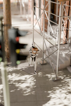 3D humanoid robot walks holding groceries near buildings