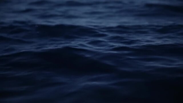 A close-up view of dark blue water, with gentle waves creating a textured surface