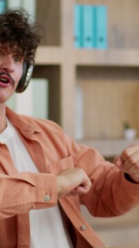 Caucasian business man funny dancing moving singing song wearing headphones humorous businessman ridiculous male guy worker listening music dance move with hands sing fooling around at table in office