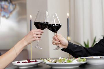 Romantic Dinner Toast with Red Wine Glasses and Candlelight Table