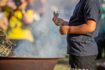 Fototapeta premium Kid hands with green branches, smoking ritual dish, Australian aboriginal smoking ceremony, ritual rite at an indigenous community event