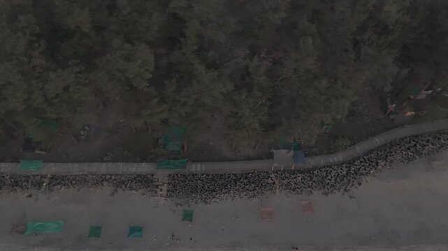 Aerial drone view of Querim Beach, North Goa, revealing a long sandy coastline with scattered rocky outcrops, rows of trees, and the Arabian Sea under soft winter evening light