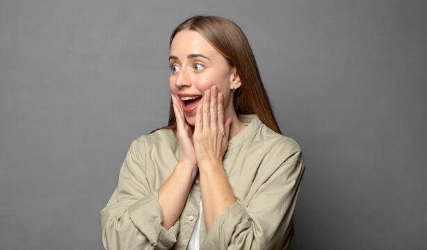 feeling happy, excited and surprised, looking to the side with both hands on face