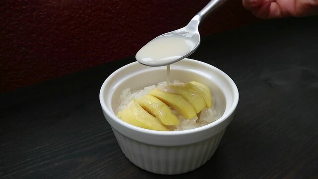 Footage of Spoon Adding Creamy Coconut Milk to Delectable Thai Sticky Rice with Durian Called Kao Niaow Turian