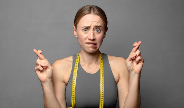 crossing fingers anxiously and hoping for good luck with a worried look. fitness concept