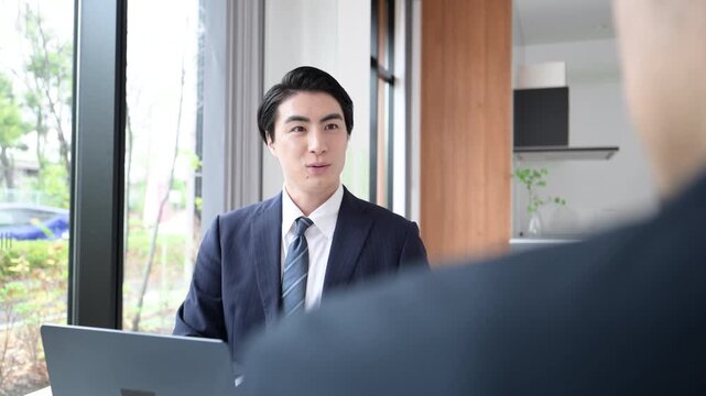 会社で商談や企画の営業をするスーツの男性、打ち合わせするビジネスマンの男性の動画	