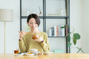 朝食で味噌汁を飲むミドルの女性