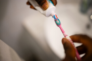 Person applying toothpaste to toothbrush for oral hygiene