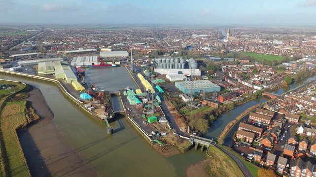 Aerial view of the bustling port, its docks filled with goods, reflecting the urban landscape merging with the tranquil river, Boston, Boston, United Kingdom.